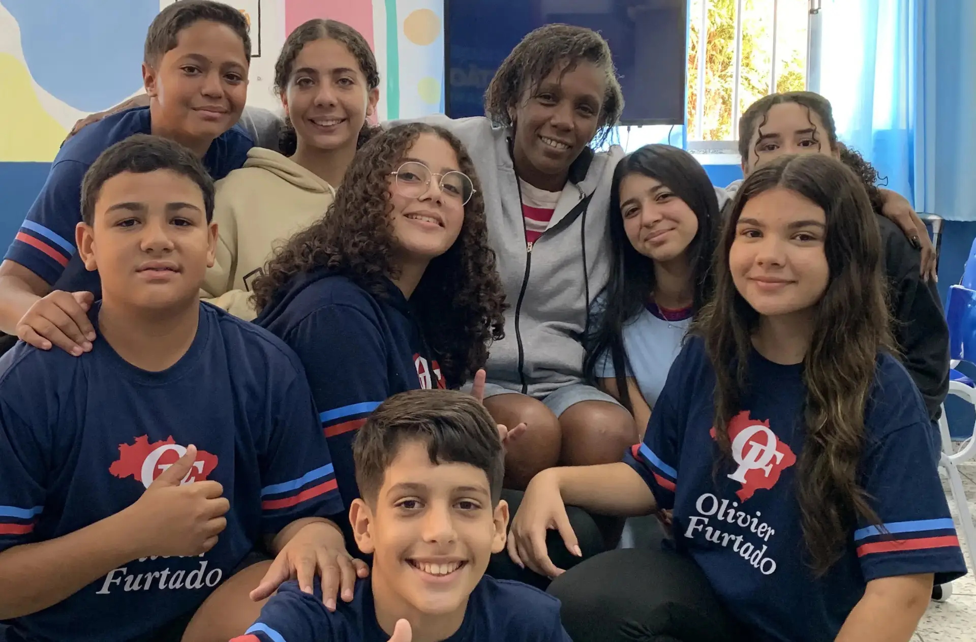 Alunos e professora da Escola Olivier Furtado sorrindo juntos